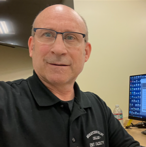 A caucasian male with glasses facing the camera and smiling.