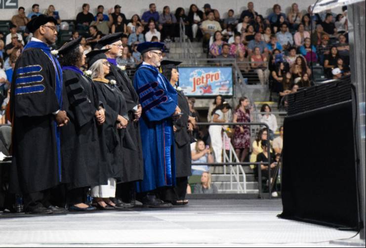 Cabinet members dressed in graduation regalia on stage