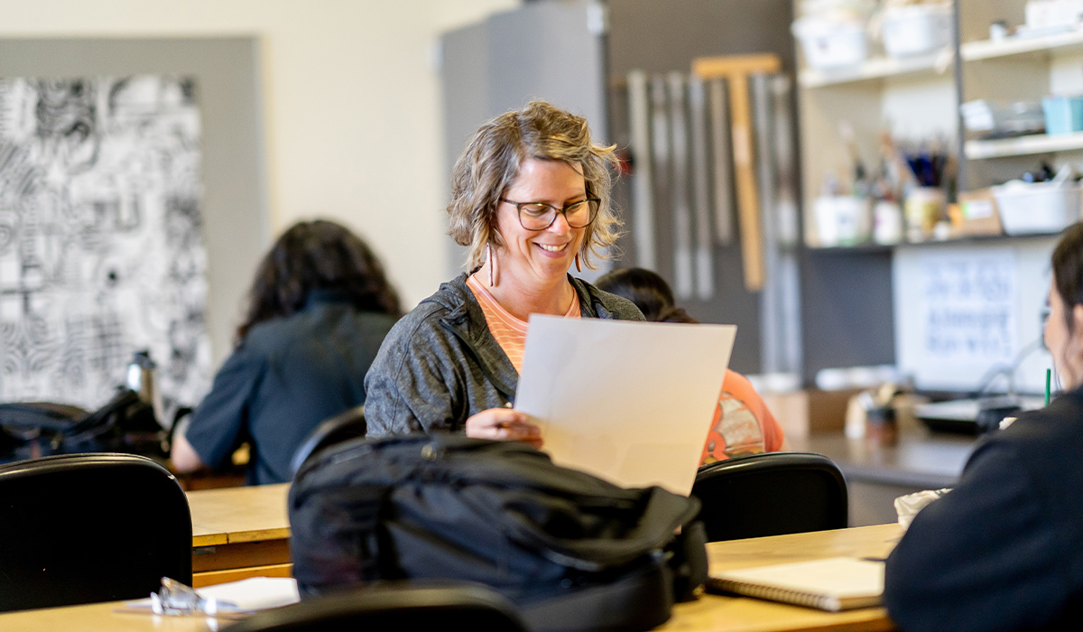 A WVC faculty member sits across from a student and looks at a paper.