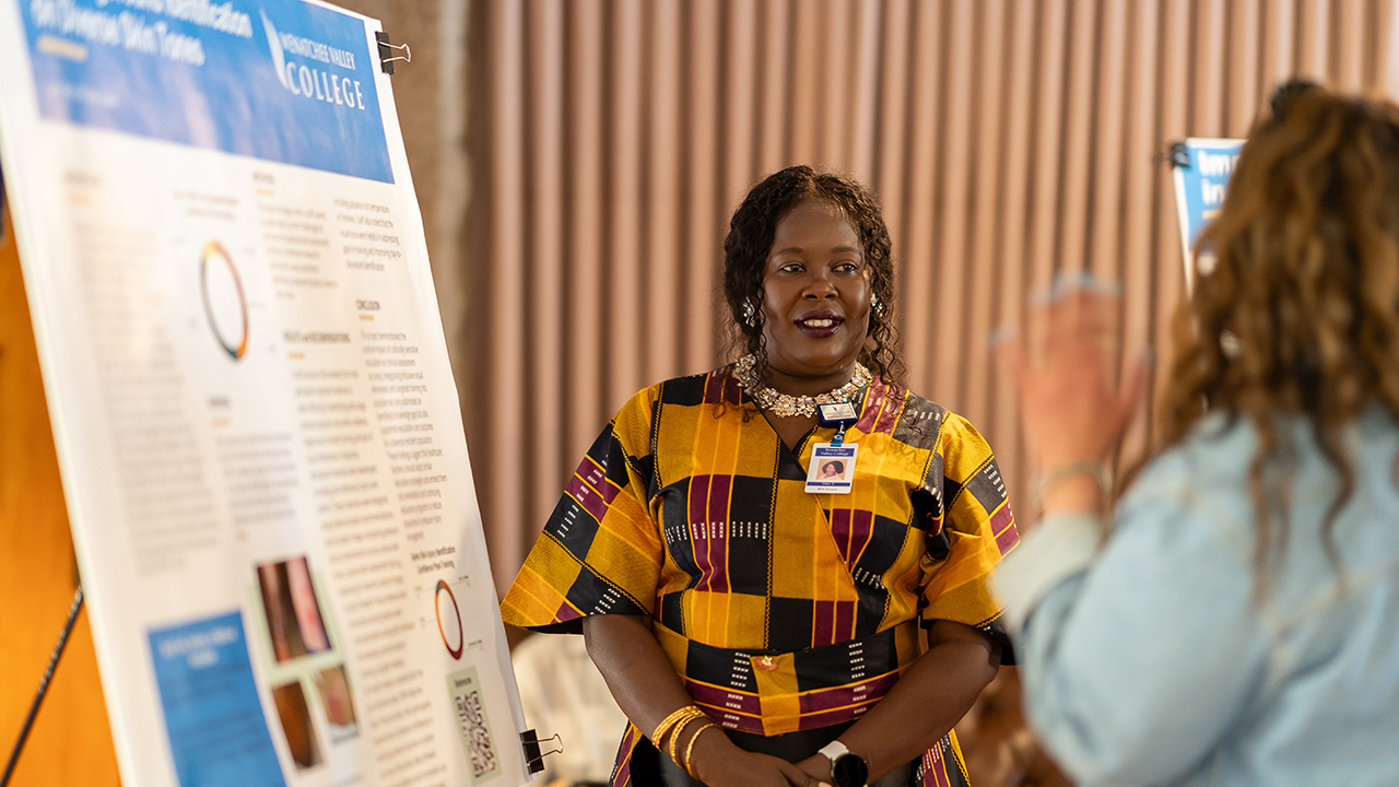 A WVC Omak LPN to BSN graduate talks with another person about her research project.