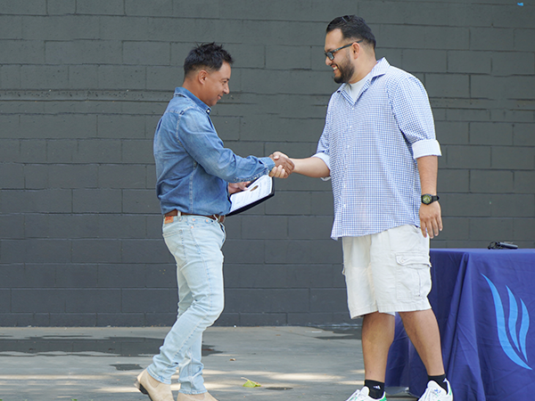 A WVC agriculture professor shakes the hand of a graduate on a stage.