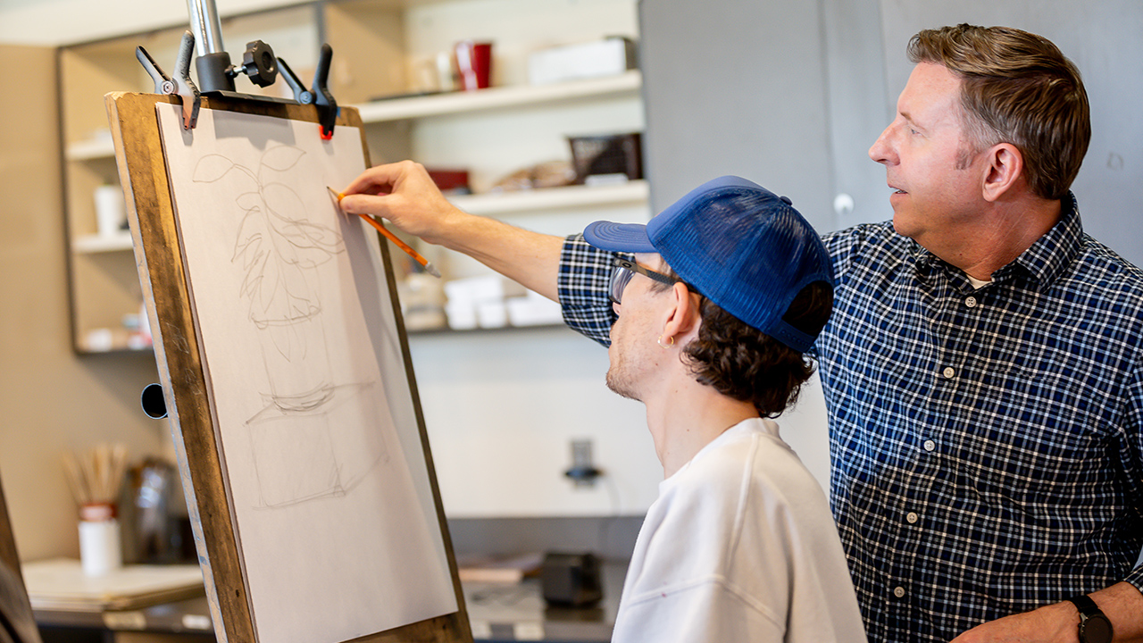 Professor Scott Bailey assists an art student with a sketch.
