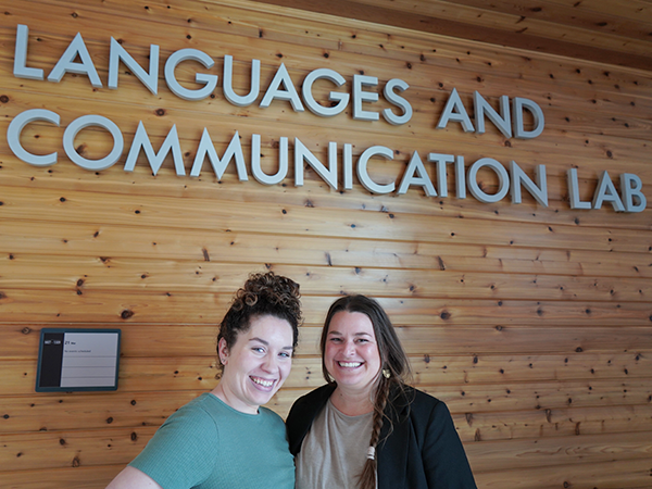 An ASL alum and instructor stand together below the Languages and Communication Lab sign.