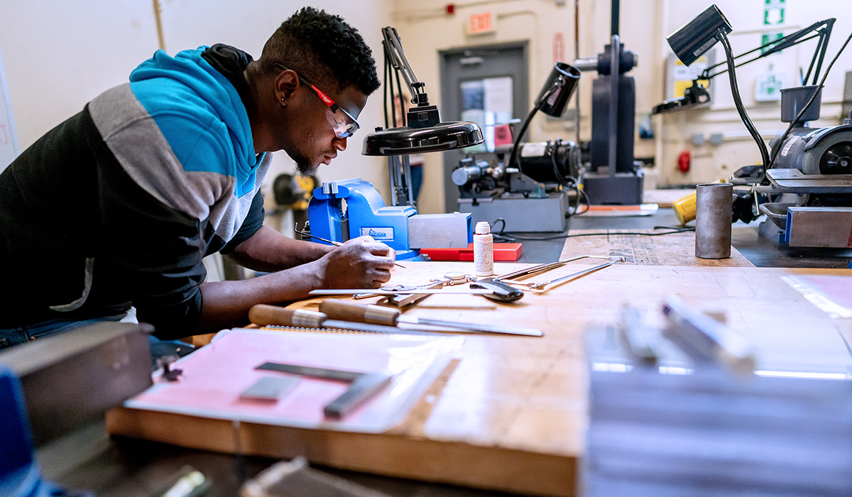 A student leans over a drafting board to study his work.