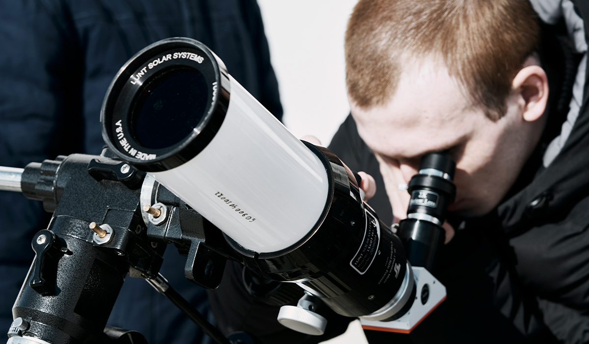 A man peers through a telescope.