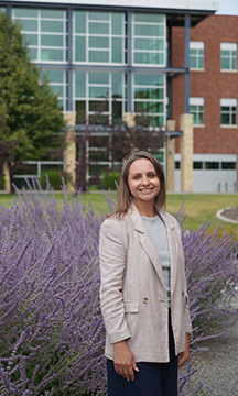 Portrait of WVC student Karyna Bukovstova standing on a gravel path with a background of purple flowers.