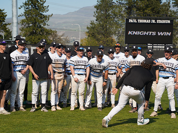 The Knights baseball team stand together with a stadium sign in the background that says 